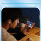 A person seated at a desk holding a smartphone that displays a colorful video game, with white wireless earbuds in their ear. The scene is framed in a rounded rectangle with a light blue border, and the text at the top reads 'Game "0" delay' with a supporting slogan below.