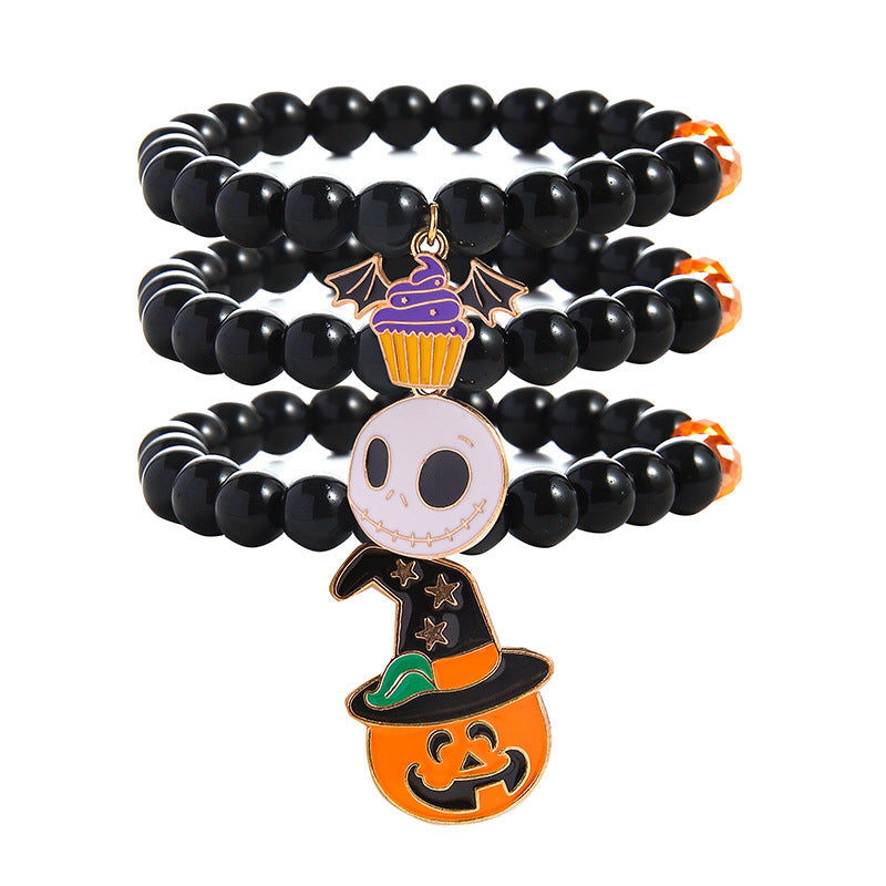 111372969-1 Three black beaded Halloween bracelets with a purple bat-wing cupcake, pale skull face and pumpkin wearing a witch hat.
