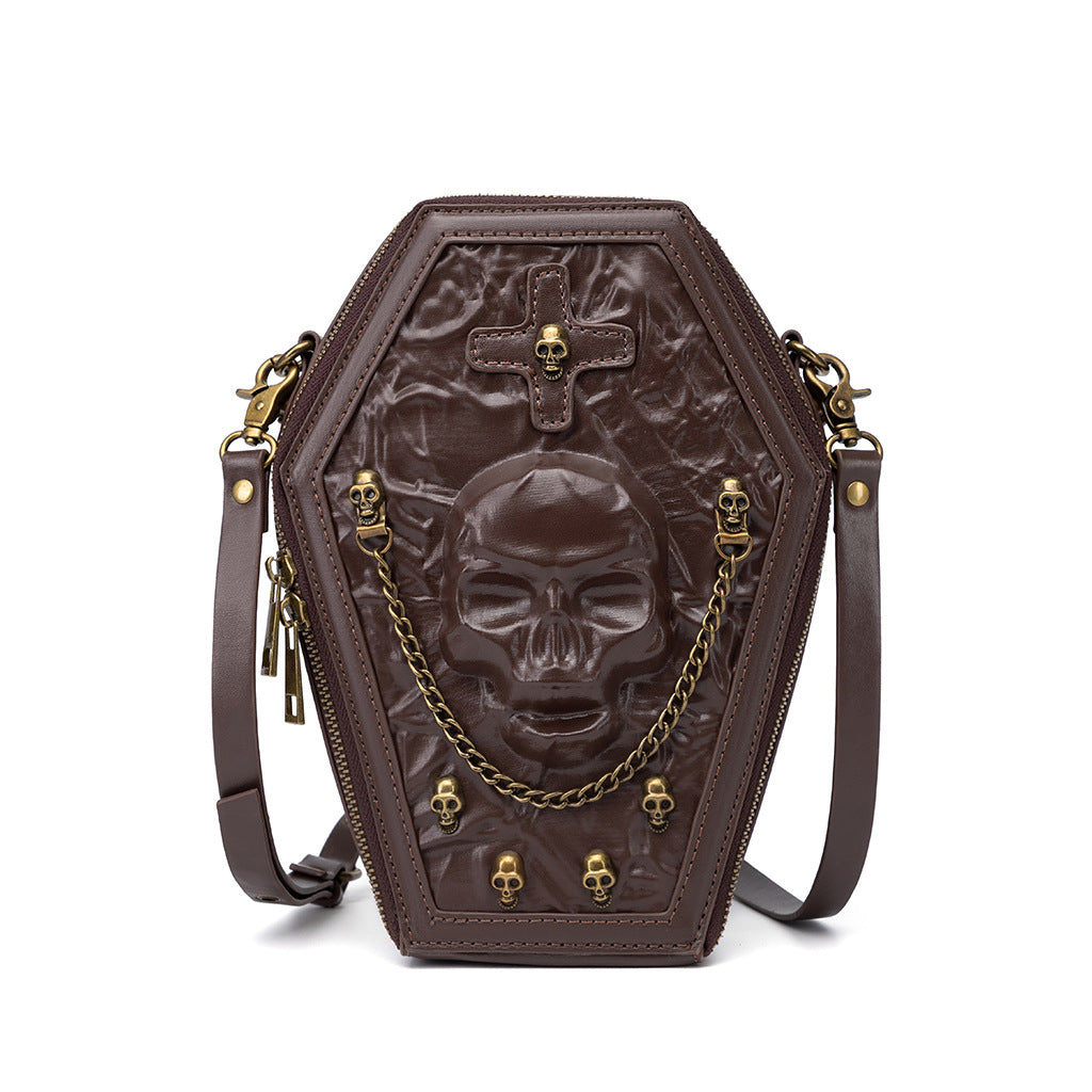 466117713-5 - Brown coffin-shaped shoulder bag with an embossed skull, cross detail, gold-tone skull studs and a draped front chain.
